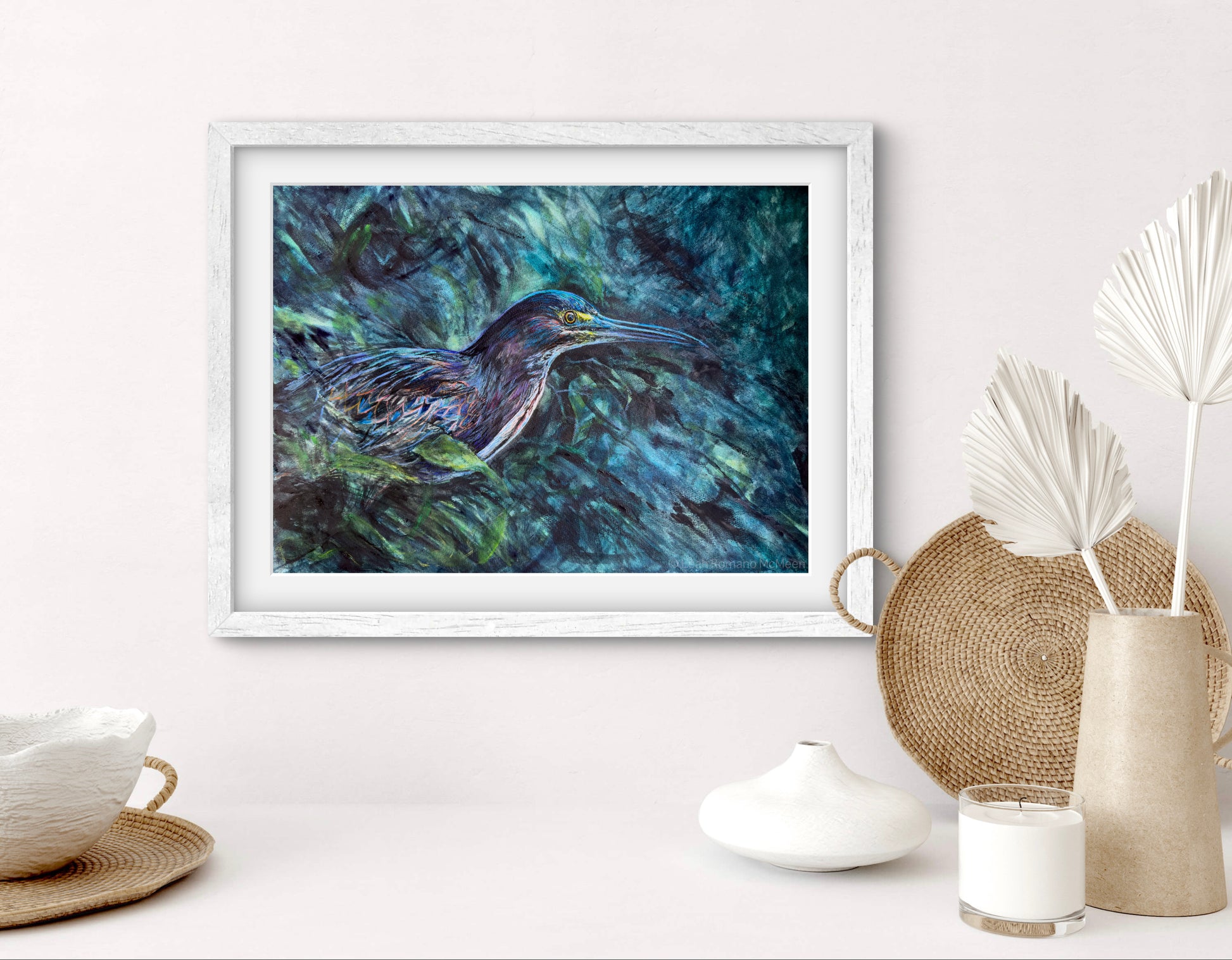 Framed artwork of a bird in water on a white wall with decorative items below.
