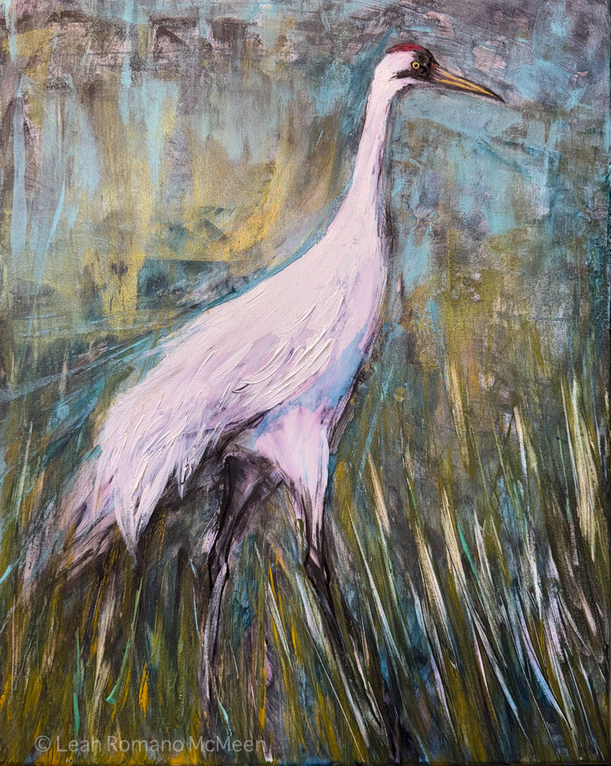 An expressive painting of a white heron standing in tall grass, with a textured background in blue, green, and yellow tones. The artist's signature 'Leah Komand McMeeon' is visible in the lower-left corner.